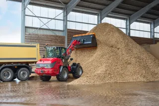 Červený nakladač Weidemann při nakládání materiálu v hale