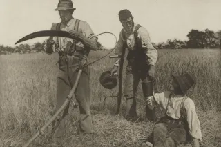 Historická fotografie rolníka s kosou na poli