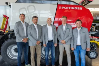 Tři zástupci společnosti Pöttinger před zemědělským strojem