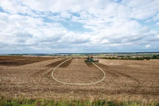Široký zemědělský pozemek se strojem na obzoru