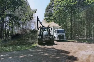 Traktor s nakládací rukou a nákladní vůz při práci v lese