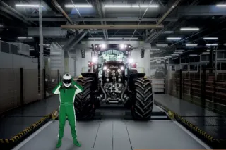 Traktor vystavený v hale za postavou závodníka.