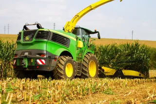 Zelená řezačka John Deere 9800 sklízí kukuřici.