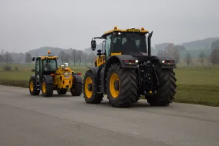 Žlutý traktor JCB Fastrac před žlutým nakladačem JCB.