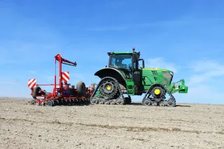 Traktor John Deere s pásovými jednotkami a secím strojem.