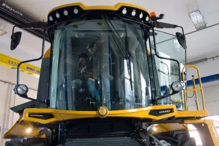 Pohled na kabinu žluté sklízecí mlátičky Sampo Comia C12 v hale.