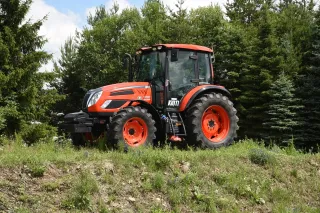 Oranžový traktor Kioti PX1153 na travnatém svahu