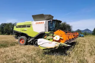 Sklízecí mlátička CLAAS Lexion s oranžovým adaptérem na poli.