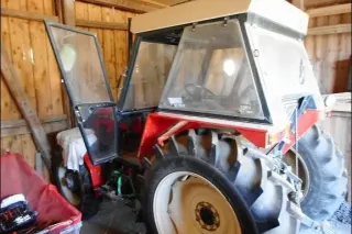 Starší traktor Zetor zaparkovaný v dřevěné stodole