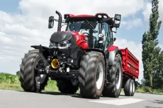Červený traktor Case IH Maxxum 145 táhnoucí návěs po silnici.