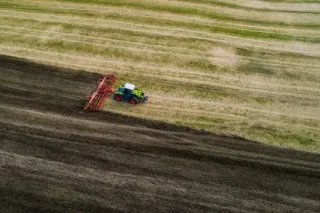Červený traktor s diskovým nářadím na poli z ptačí perspektivy