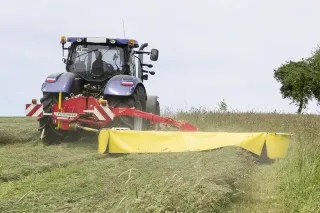 Traktor se žacím strojem Pöttinger při sečení louky