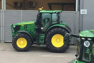 Zelený traktor John Deere před šedou budovou