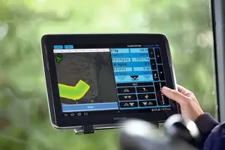 Ruka ovládá tablet s aplikací pro zemědělský stroj