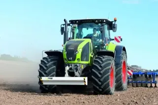 Traktor Claas s modrým půdozpracujícím strojem na poli