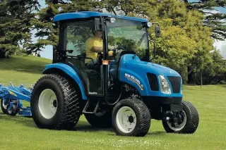 Modrý traktor New Holland Boomer na trávníku