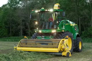 Zelená sklízecí řezačka John Deere na louce