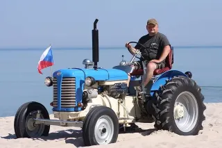 Muž na modrém historickém traktoru Zetor 25 na pobřeží
