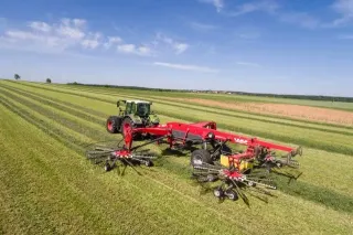 Traktor se čtyřrotorovým shrnovačem Fella na louce