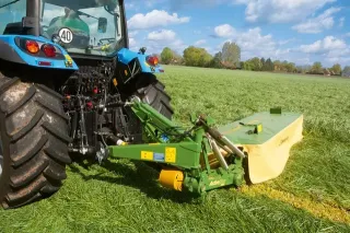 Detail zadní části modrého traktoru se žacím strojem Krone
