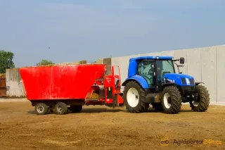 Modrý traktor New Holland s červeným krmným vozem