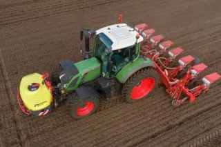 Zelený traktor Fendt s červeným secím strojem Kverneland na poli