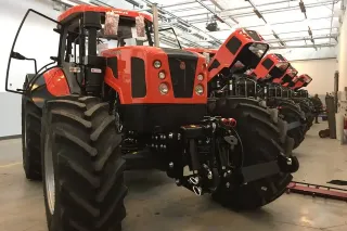 Řada červených traktorů Ursus ve výrobní hale