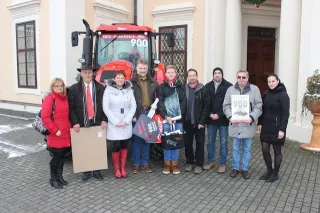 Skupina lidí před červeným traktorem Zetor s označením 900