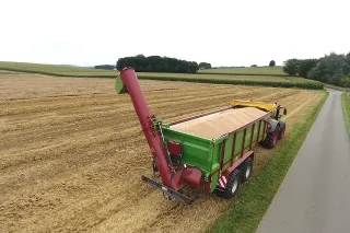 Zelený vůz Strautmann Aperion za traktorem na poli