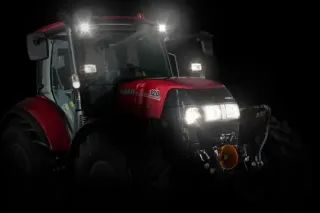 Červený traktor Case IH Luxxum s rozsvícenými světly