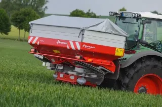 Traktor s rozmetadlem hnojiv Kverneland na louce