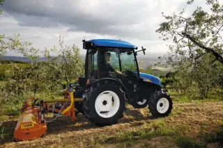 Modrý traktor New Holland v sadu