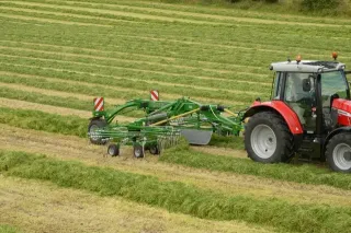 Červený traktor s připojeným zeleným shrnovačem píce McHale