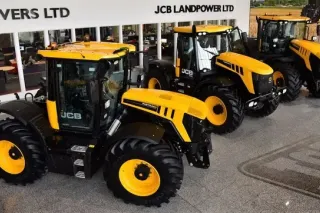 Žluté traktory JCB Fastrac před budovou