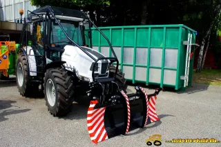Bílý traktor s čelním zařízením a zelenou nástavbou na výstavě Agrokomplex