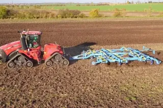 Pásový traktor Case IH táhne modrý kypřič Farmet při polní ukázce