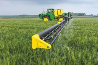 Zelený samojízdný postřikovač John Deere v obilí