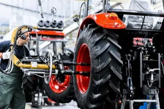 Pracovník u zadního kola traktoru Zetor ve výrobě