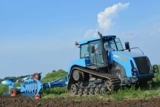 Modrý pásový traktor Agromash s pluhem