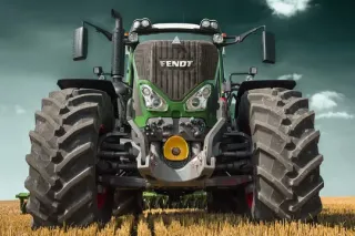 Zelený traktor Fendt se širokými koly čelně na poli