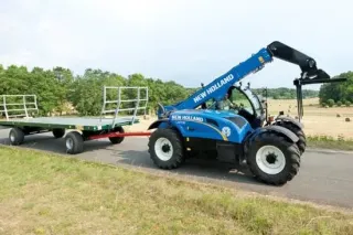 Modrý teleskopický manipulátor New Holland táhne přívěs