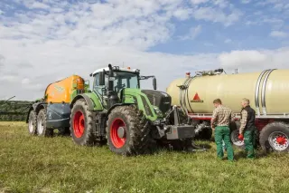 Traktor Fendt s cisternou stojí vedle druhé cisterny a dvojice pracovníků.