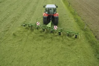 Traktor s obracečem píce Krone na louce