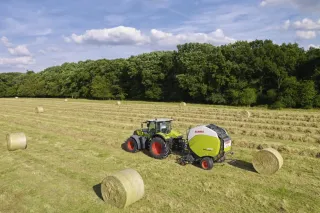 Traktor Claas s lisem na válcové balíky na louce