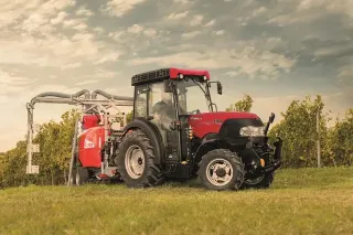 Červený traktor Case IH s postřikovačem ve vinici
