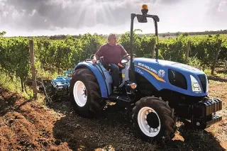 Modrý traktor New Holland v řádcích vinice
