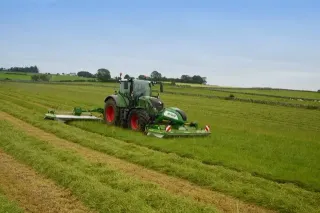 Zelený traktor Fendt se žacími stroji při sečení louky