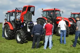 Návštěvníci si prohlížejí červené traktory Zetor na předváděcí akci