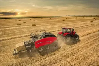 Červený traktor Case IH s lisem na balíky při sklizni