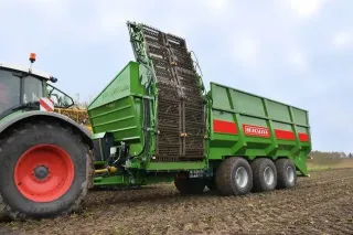 Zelený překládací vůz Bergmann za traktorem na poli